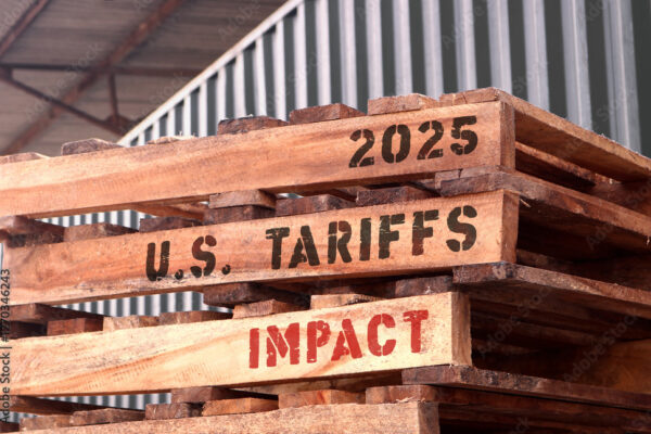 2025 U.S Tariffs impact, text written on piled up pallets. Trade and supply chain concept.