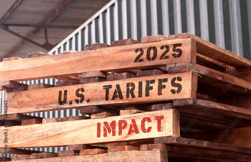 2025 U.S Tariffs impact, text written on piled up pallets. Trade and supply chain concept.
