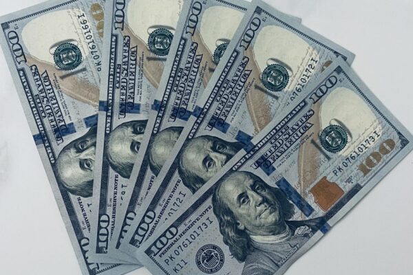 Five one hundred dollar US bills fanned out on a marble background. (Please note rules for using photos of US currency here https://www.bep.gov/currency/currency-image-use)