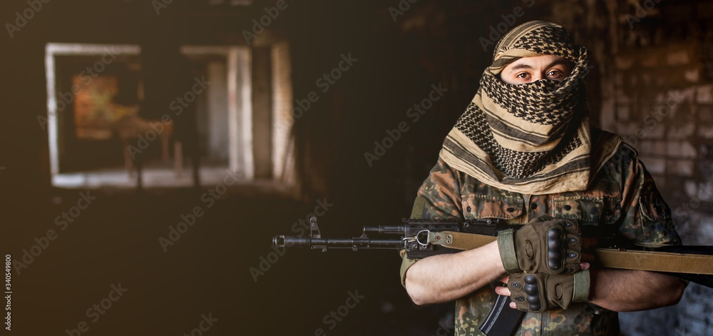 Arab male soldier in a headdress from the national keffiyeh with a weapon in his hands man with a gun on a black background