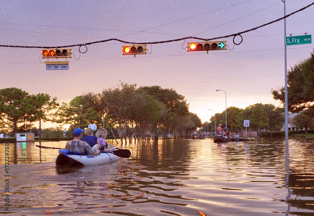 HOUSTON, USA - SEPTEMBER 2, 2017: Working traffic lights over flooded Houston streets and boats with people at sunset